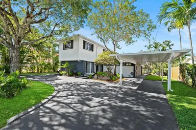 Circular driveway, covered carport & curated tropi