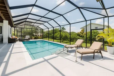 Screen-enclosed pool with travertine deck surround
